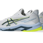 Innebandysko i vitt med Asics-design i blått och lime, välvd sula och snörning.